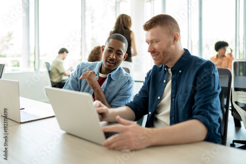 Businessmen collaborating on laptop in modern office