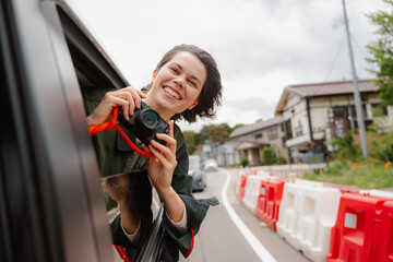 A woman takes pictures from a car