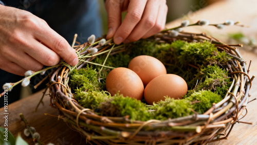 Hands crafting rustic pussy-willow nest with moss and eggs, DIY Easter decor tutorial scene for craft blog or workshop