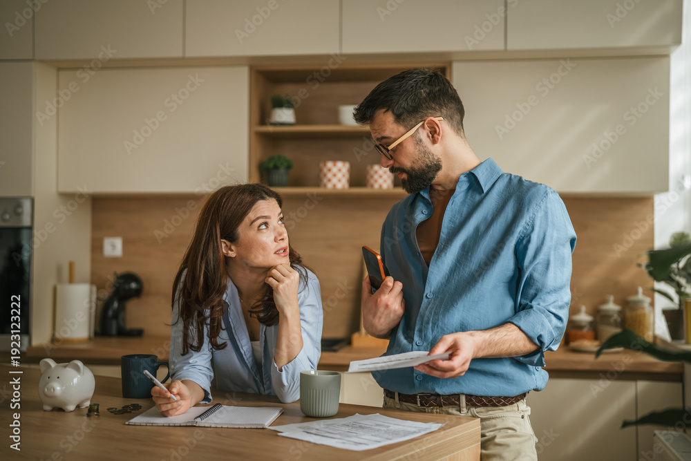 Fototapeta premium Couple discussing home finances and managing budget in kitchen