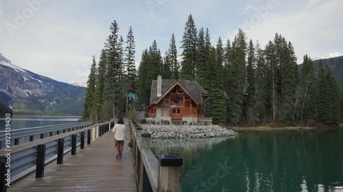 Wallpaper Mural Woman and dog walking on a wooden bridge towards a lodge on Emerald Lake in Yoho National Park Torontodigital.ca