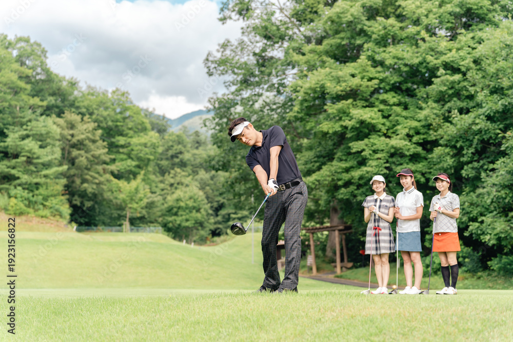 Obraz premium A male golfer hitting a tee shot at a golf course with his companion watching his swing
