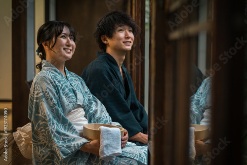 Fotografie Couples in yukata enjoying the cool evening breeze on the veranda of a hot sprin