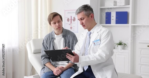 Urologist with clipboard consulting patient on medical couch in clinic