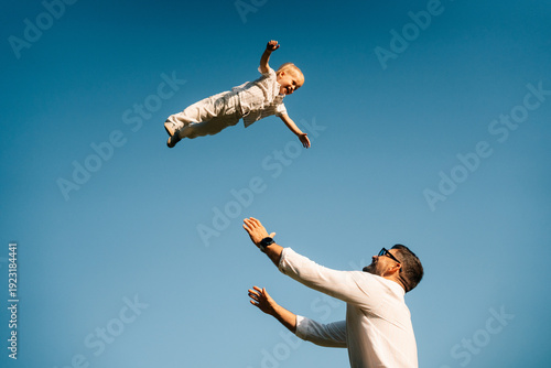 Father Throws Son in the Air on a Sunny Day Outdoors