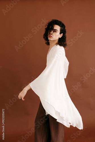 Queer man posing in white flowy fashion top