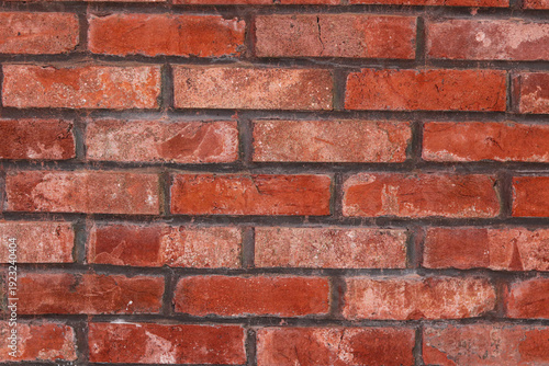 A full-frame background of a red brick wall, showcasing the rough, porous texture of the bricks and the contrasting black mortar.