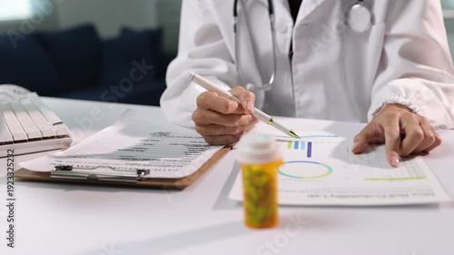 The doctor is analyzing the results of a drug trial. Female physician examining patient's medical data and graphs on her desk.