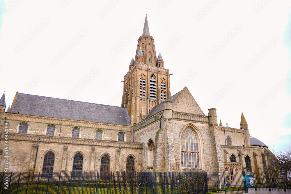 Obraz premium Historic stone church with tall bell tower under cloudy sky Calais France