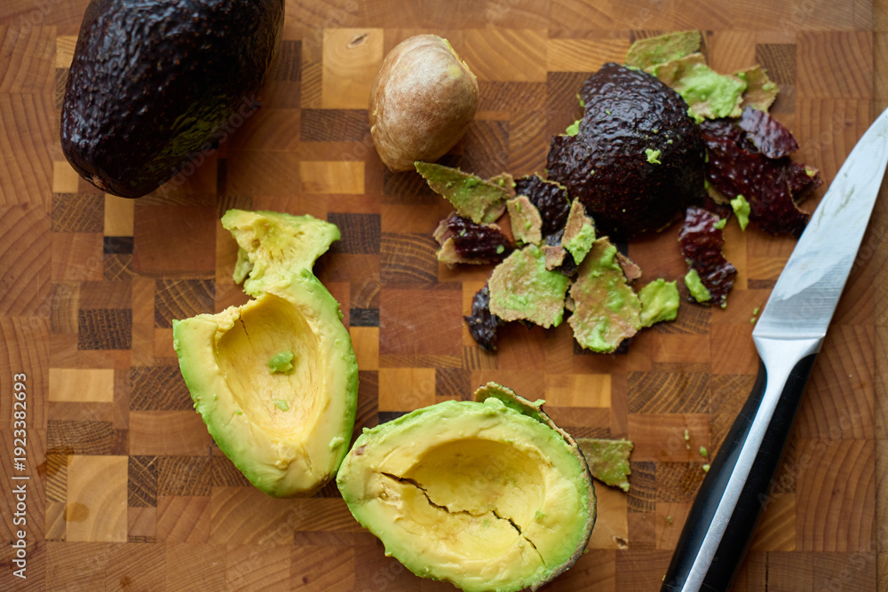custom made wallpaper toronto digitalAvocado halves with pit, peel scraps and knife on wooden cutting board. Concept of food preparation, healthy cooking and guacamole