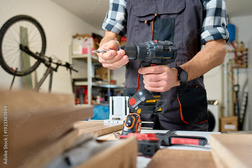 Ταπετσαρία Carpenter in workwear holding cordless drill over workbench with wood boards and tools