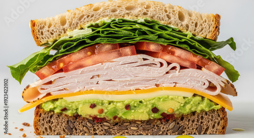 A delicious sandwich with turkey, cheese, avocado, tomato, and lettuce on whole grain bread