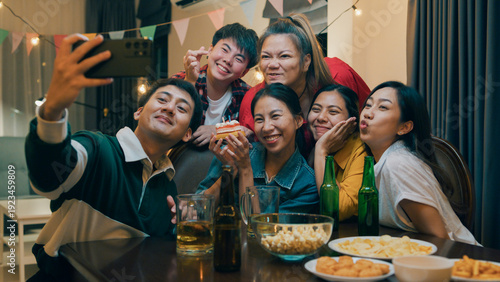Obraz na plátně Group of young adult Asia friend with birthday cake look at camera shooting video photo on mobile app fun hangout party in night life indoor home