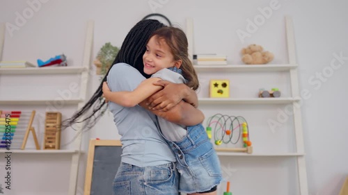 Caucasian little girl hugs her African tutor after learning activity. 