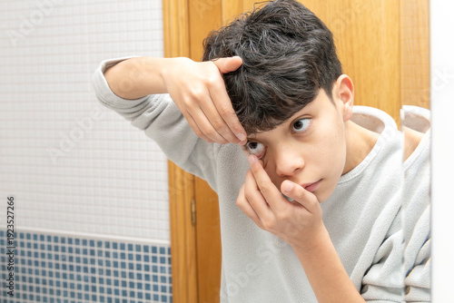 Bilde på lerret Teenager boy learning to insert contact lens, managing vision correction
