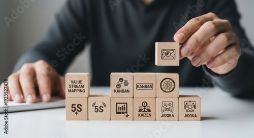 Lean management philosophy and showing cubes arranged to eliminate all waste using wooden cubes, symbolic icons, human hand, natural depth of field, soft blurred background, minimal desk background.