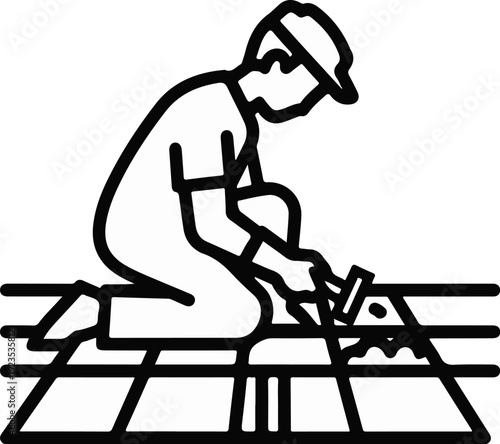 A person in a cap and gloves is laying tiles on a grid