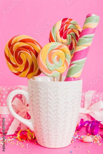 Wallpaper Mural Colorful candies in cup on table on light background background. Large swirled lollipops. Creative concept of a jar full of delicious sweets from the candy store Torontodigital.ca