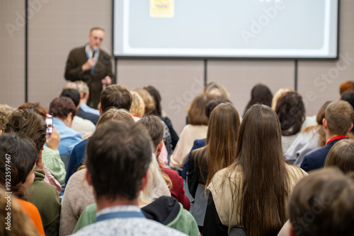 Wallpaper Mural Crowd seated listening to presenter during business conference seminar, focused audience, professional networking atmosphere. Torontodigital.ca