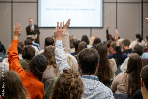 Foto Audience at conference raising hands to ask questions during presentation, engaged participants in meeting room, interactive seminar atmosphere