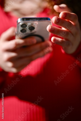 Woman Using Smartphone With Curly Hair Wearing Red Sweater IndoorsDays