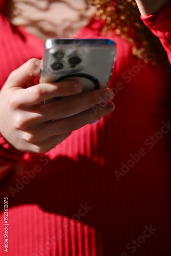 Woman Using Smartphone With Curly Hair Wearing Red Sweater IndoorsDays