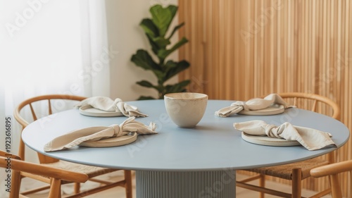 A modern dining table setting with minimalist placemats, napkins and a central bowl.
