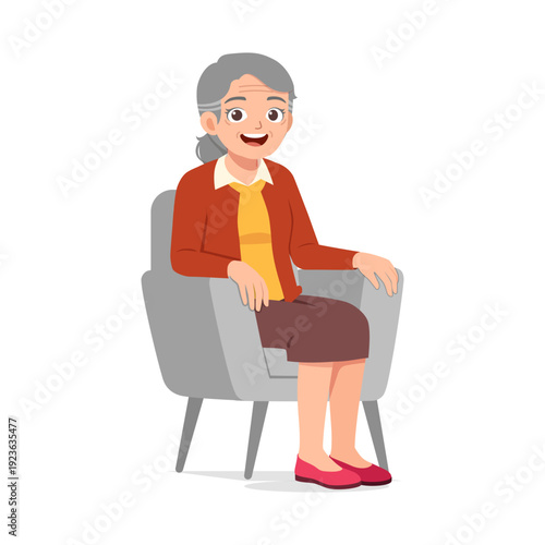 Happy smiling senior Asian woman sitting comfortably in a grey armchair looking content and relaxed