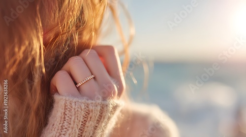 A woman with long hair is wearing a gold ring on her finger