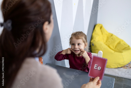 Speech therapist working with a young child on communication skills and speech development, using alphabet cards to enhance the learning process and articulate sounds