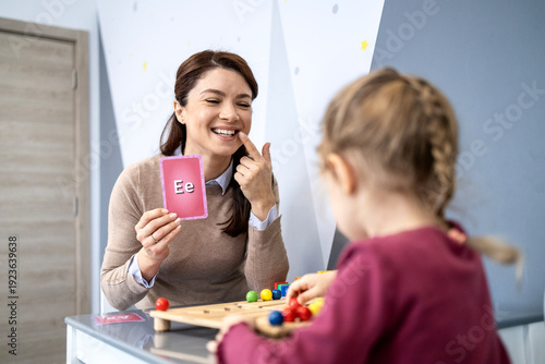 Foto Speech therapist teaching child articulation using flashcard with letter e, demo