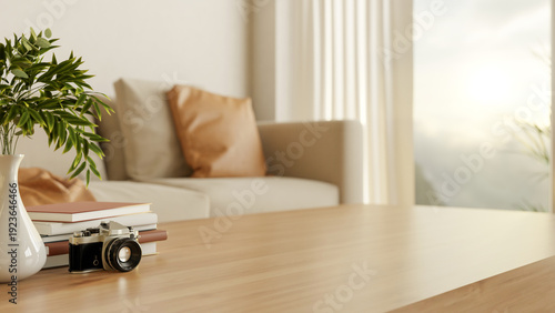 Canvastavla Camera with book and vase on wooden table with sofa couch and sunlight through w
