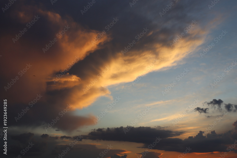 Fototapeta premium Dark dramatic storm clouds mixed with warm sunset light