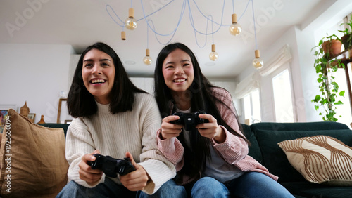Obraz na płótnie Diverse women enjoying multiplayer video game on sofa at home