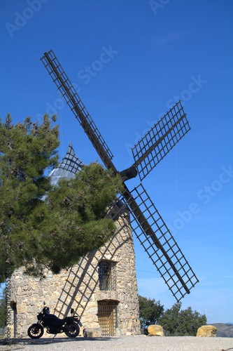 An old windmill in sunny weather and a motorcycle