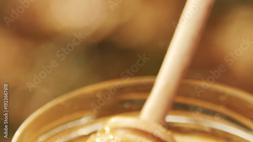 Wallpaper Mural Close-up detailed view of a beekeeper's hand stirring dark amber buckwheat honey in a glass jar at the apiary, showcasing the thick texture, Torontodigital.ca