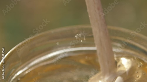 Wallpaper Mural Close-up detailed view of a beekeeper's hand stirring golden acacia honey in a glass jar at the apiary, showcasing the texture Torontodigital.ca