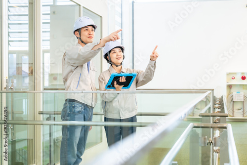 タブレットPCを持ってビルの屋内に立つ男女エンジニア