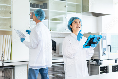 厨房をチェックする衛生白衣を着た男女作業員