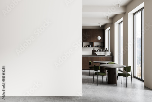 Contemporary minimalist kitchen interior with round dining table, green chairs, and a large empty white wall for poster mockup or design template. 3D Rendering