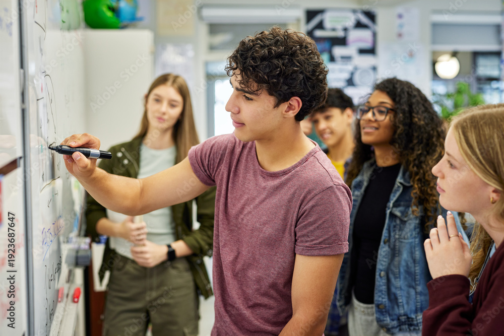 Naklejka premium Teen Student solving math equation on whiteboard at high school