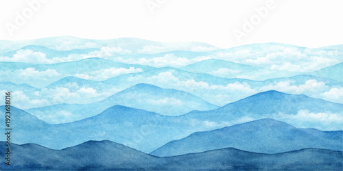 A misty winter morning reveals a blue mountain landscape where snow-covered peaks and silhouettes of hills pierce through a soft fog under a vast nature sky filled with clouds at sunrise