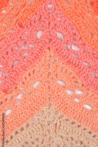 Detailed view of a handmade crochet fabric featuring a geometric lace pattern with a warm ombre transition from cream to vibrant pink