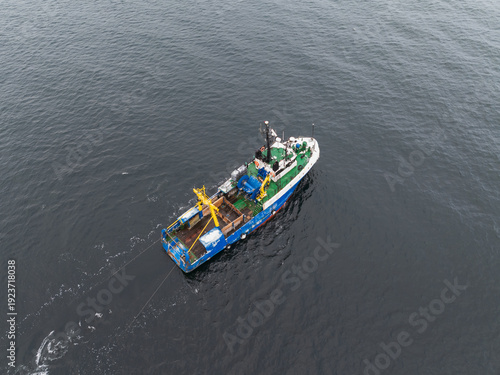 Foto Aerial drone view of a fishing trawler vessel pulling nets in the open Baltic Se