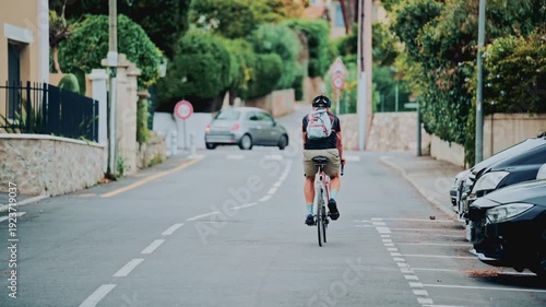 Wallpaper Mural Cyclist riding bicycle on suburban street with trees and parked cars Torontodigital.ca