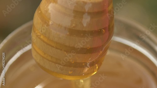 Wallpaper Mural Close-up detailed view of a beekeeper's hand stirring pale golden linden honey in a glass jar at the apiary Torontodigital.ca