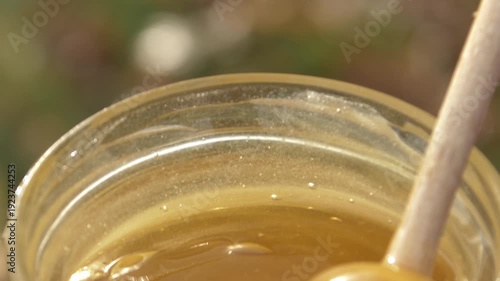 Wallpaper Mural Close-up detailed view of a beekeeper's hand stirring creamy white rapeseed honey in a glass jar at the apiary, showcasing the smooth texture Torontodigital.ca