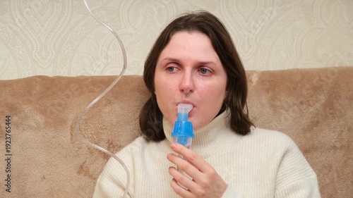 Woman using medical nebulizer for inhalation treatment at home. Healthcare and respiratory therapy for asthma or cold.