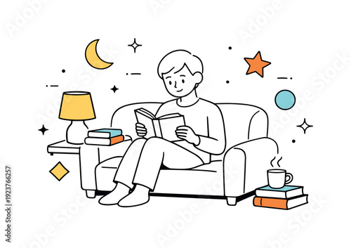 Young man relaxing on a comfortable couch reading a book with a cup of tea nearby