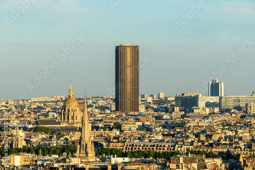 Foto Wide Paris cityscape featuring the gleaming dome of Les Invalides and the tall Montparnasse Tower rising above layered rooftops in soft evening sunlight